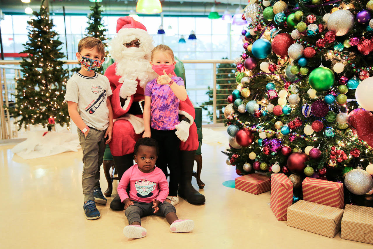 Santa poses with visitors of the North Pole Exhibit, Fletcher Collins, Quinn Collins and Ruthie Collins.