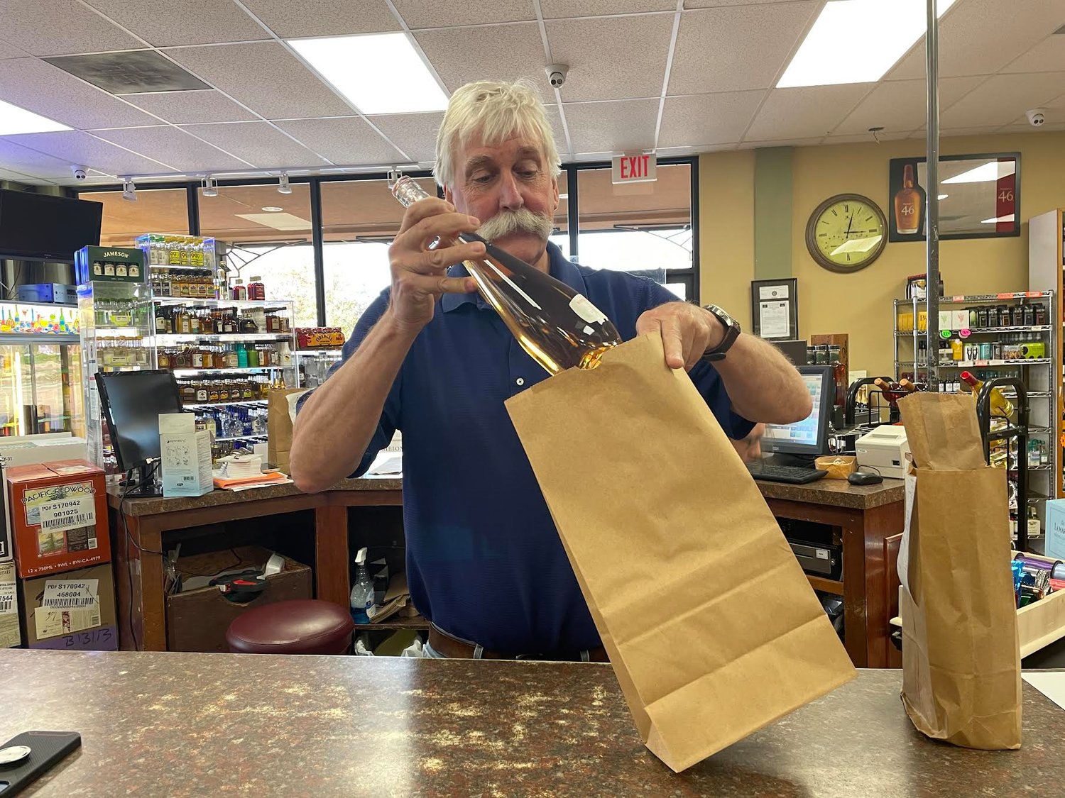 Madison Cellars owner Pete Clark packages up a bottle of wine for delivery.