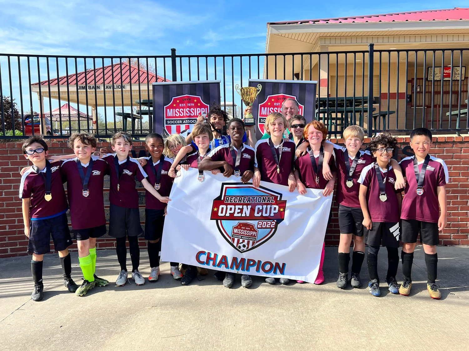 The Maroon Power Rangers pose after winning the U-12 Boys Division of the Mississippi Soccer Association's Recreational Open Cup 2022. Pictured, from left: Ian Zhang, Haden Mote, Michael Kramen, Laurence Stamps, McKellar Goff, Silas Luckett, Wilson Morataya (Assistant Coach), Correy Elder, Talon Gust,  Kevin Crothers (Head Coach), Brendan Campbell, Quest Crothers, Solomon Voborsky, Jude Jamileh, Lemuel Shi.