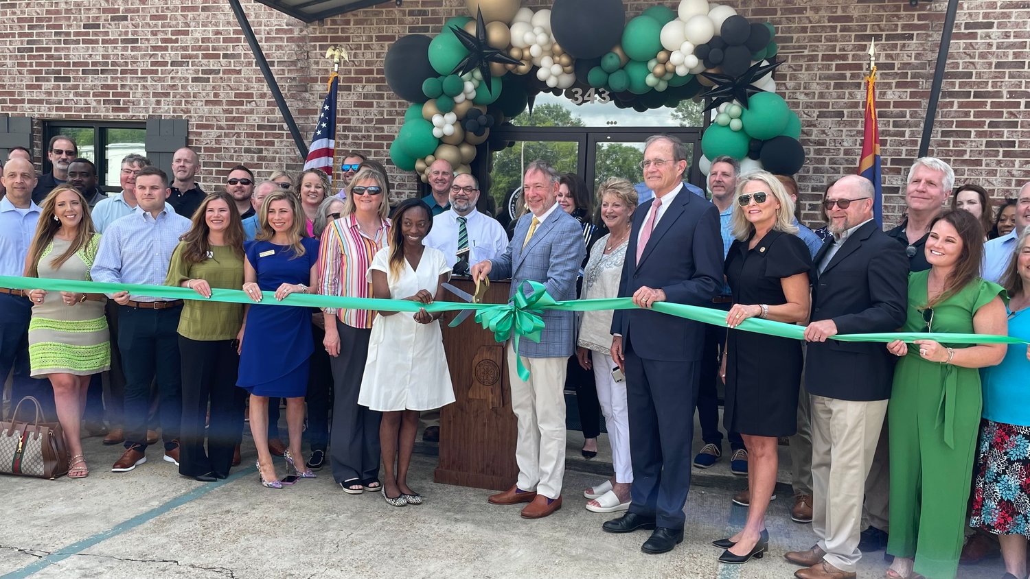 Gluckstadt Mayor Walter Morrison, center with scissors, prepares to cut the ribbon on Gluckstadt City Hall. City aldermen, Lt. Gov. Delbert Hosemann, State Rep. Jill Ford and local business leaders joined in on the celebration.
