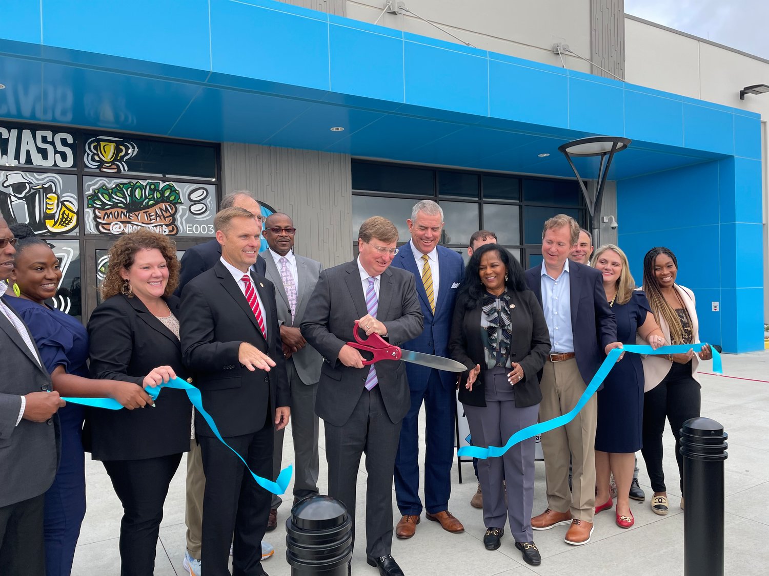 Gov. Tate Reeves, middle, flanked by U.S. Rep. Michael Guest, Lt. Gov. Delbert Hosemann, Speaker of the House Philip Gunn and a host of other county and business leaders cut the ribbon on the new Amazon distribution facility in Madison County last week.