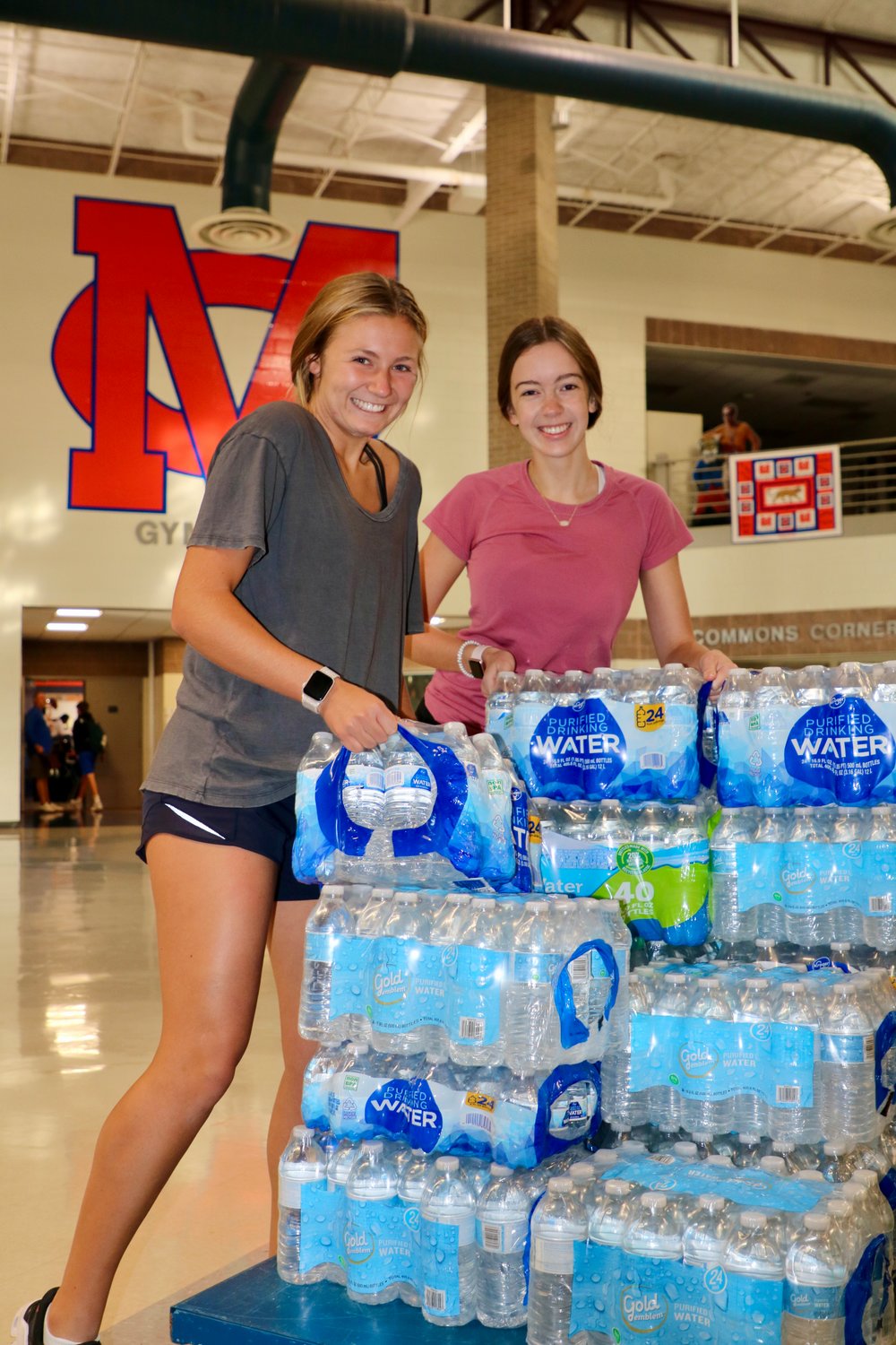 Madison Central seniors Alexa Ainsworth and Mary Claire Butts drop off water in the school foyer for the JPS water drive.