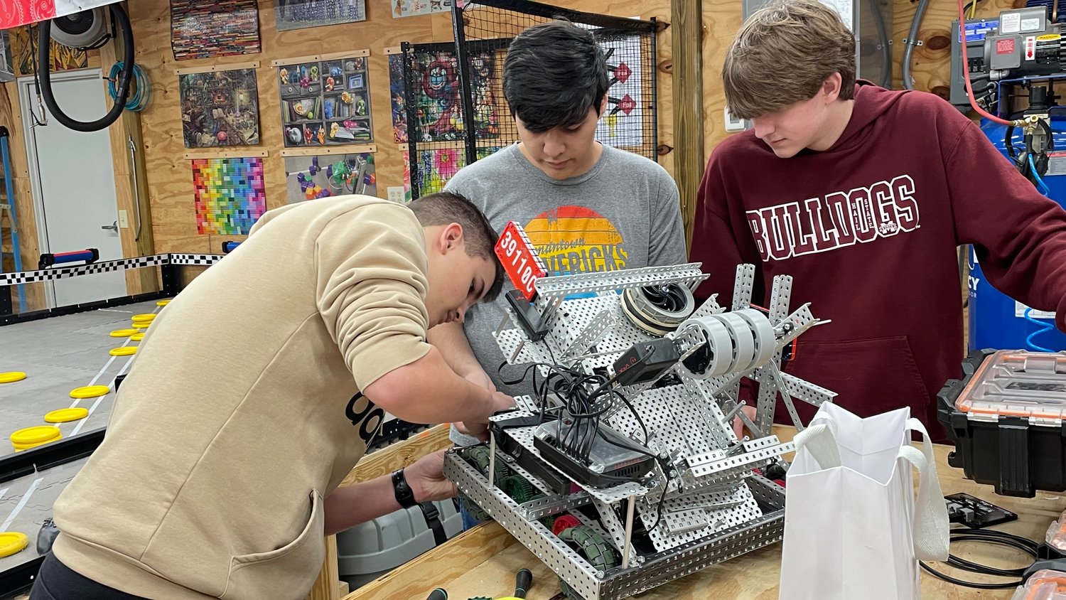 Crosby Petro, Emiliano Valdez, and Ethan Knight tinker with the robot they used to compete in the MCS VEX Robotics tournament.