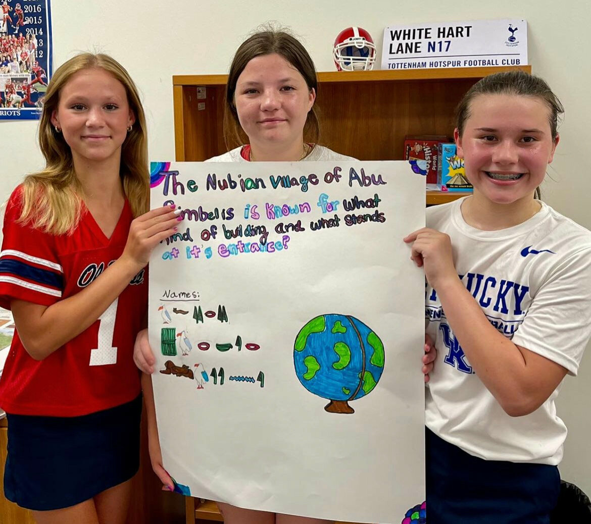 Madison residents Layne Canada, left, and Avery Warf, right, stand with their classmate Parker Reynolds (center) at Jackson Prep with one of the questions they asked their librarian, Norma Cox, while she was in Egypt.